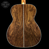 Close-up of a wooden acoustic guitar back with 'Tone Shop' logo.