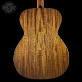 Close-up of a wooden acoustic guitar body with 'Tone Shop' logo.