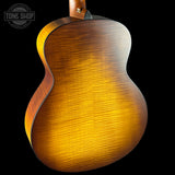 Close-up of a wooden acoustic guitar body with a visible brand logo in the corner.