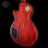 Close-up of a red electric guitar with a visible brand logo on a black background