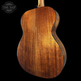 Close-up of a wooden acoustic guitar on a black background with 'Tone Shop' logo.