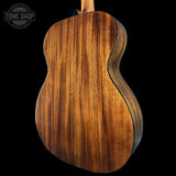 Close-up of a wooden acoustic guitar body with 'Tone Shop' logo.