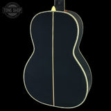 Back view of a black acoustic guitar with a visible brand logo in the corner.