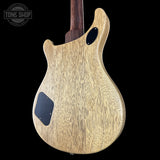 Back view of a guitar with a wood finish on a black background, featuring the Tone Shop logo.