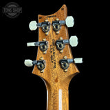 Guitar headstock with 'Custom Built' engraving on a black background, featuring the Tone Shop logo.