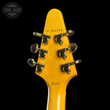 Close-up of a yellow guitar headstock with tuning pegs on a black background, featuring the Gibson logo.