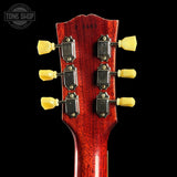 Close-up of a red guitar headstock with yellow tuning pegs on a black background, featuring 'Tone Shop' logo.