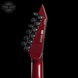 Close-up of a red electric guitar headstock with brand logo on a black background