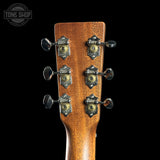 Close-up of a guitar headstock with tuning pegs on a black background, featuring the Tone Shop logo.
