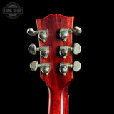 Close-up of a red guitar headstock with tuning pegs on a black background, featuring 'Tone Shop' branding.