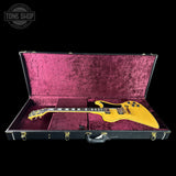 Yellow electric guitar in a black case with purple interior, Tone Shop logo visible.