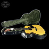 Acoustic guitar in a hard-shell case with 'Tone Shop' logo in the corner.