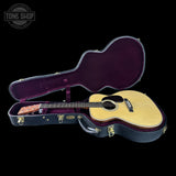 Acoustic guitar in an open case with 'Tone Shop' logo in the corner.