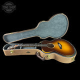 Acoustic guitar in a hard-shell case with 'Tone Shop' logo.