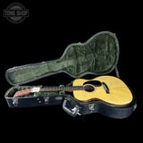 Acoustic guitar in a hard-shell case with 'Tone Shop' logo in the corner.