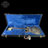 Guitar in a blue-lined case with 'Tone Shop' logo.