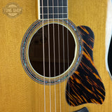 Close-up of an acoustic guitar's soundhole and body with a 'Tone Shop' logo.