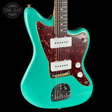 Turquoise electric guitar with a dark wood finish on a black background, featuring the Tone Shop logo.