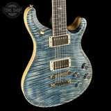 Blue electric guitar with a wavy pattern on a black background, featuring the Tone Shop logo.