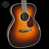 Acoustic guitar with a sunburst finish on a black background, featuring the Tone Shop logo.