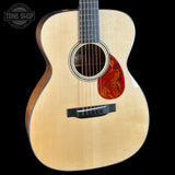 Acoustic guitar with a flame maple top on a black background, featuring the Tone Shop logo.