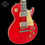 Red electric guitar with gold hardware on a black background, featuring 'Tone Shop' logo.