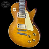 Gibson Les Paul electric guitar with a sunburst finish on a black background, featuring the Tone Shop logo.