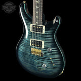 Blue electric guitar with a black background, featuring the Tone Shop logo.