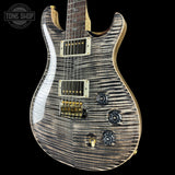 Electric guitar with a wavy wood finish on a black background, featuring the Tone Shop logo.