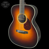 Acoustic guitar with a sunburst finish on a black background, featuring the Tone Shop logo.
