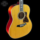 Acoustic guitar with a red accent on a black background, featuring the Tone Shop logo.