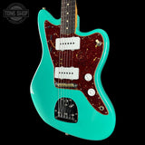 Turquoise electric guitar with a dark wood finish on a black background, featuring the Tone Shop logo.