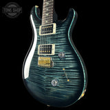 Blue electric guitar with a wavy finish on a black background, featuring 'Tone Shop' branding.