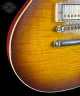 Close-up of a sunburst electric guitar with 'Tone Shop' logo.