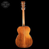 Back view of a wooden acoustic guitar with 'Tone Shop' logo in the corner.