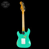 Turquoise electric guitar with a worn finish on a black background, featuring 'Tone Shop' logo.
