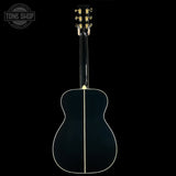 Back view of an acoustic guitar with a clear finish on a black background, featuring the Tone Shop logo.