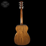 Back view of a wooden acoustic guitar with 'Tone Shop' logo in the corner.