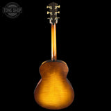 Back view of a wooden acoustic guitar on a black background with 'Tone Shop' logo.