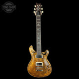 Electric guitar with a wood finish on a black background, featuring the Tone Shop logo.