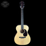 Acoustic guitar with a black pickguard on a white background, featuring the Tone Shop logo.
