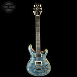 Electric guitar with a blue flame finish on a black background, featuring the Tone Shop logo.