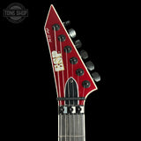 Close-up of a red electric guitar headstock with tuning pegs on a black background, featuring 'Tone Shop' branding.