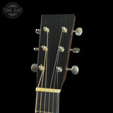 Close-up of a guitar headstock with tuning pegs on a black background, featuring the Tone Shop logo.