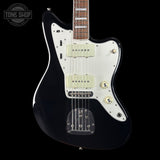 Black electric guitar with a white pickguard on a black background, featuring 'Tone Shop' branding.