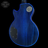 The back of an electric guitar with a vibrant blue flame finish and a silver 'Gibson' logo badge, shown against a solid black background.