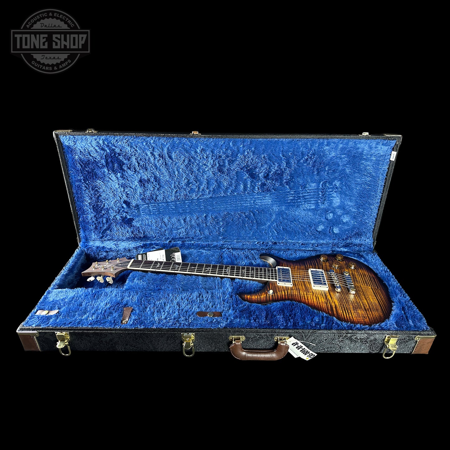 Guitar in a blue-lined case with 'Tone Shop' logo.
