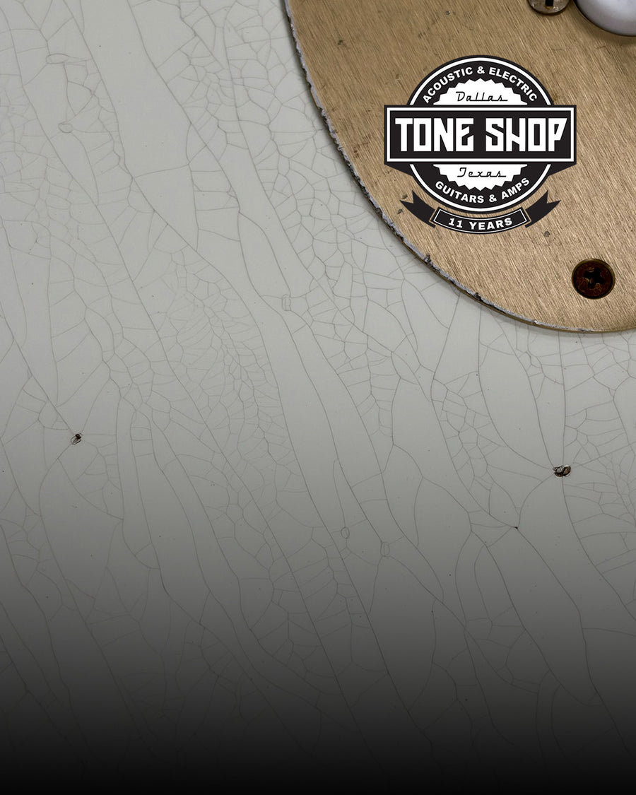 Close up details of white guitar with checked finish, and bronze pickguard with Tone Shop Guitars 11 Years badge at the top right corner.