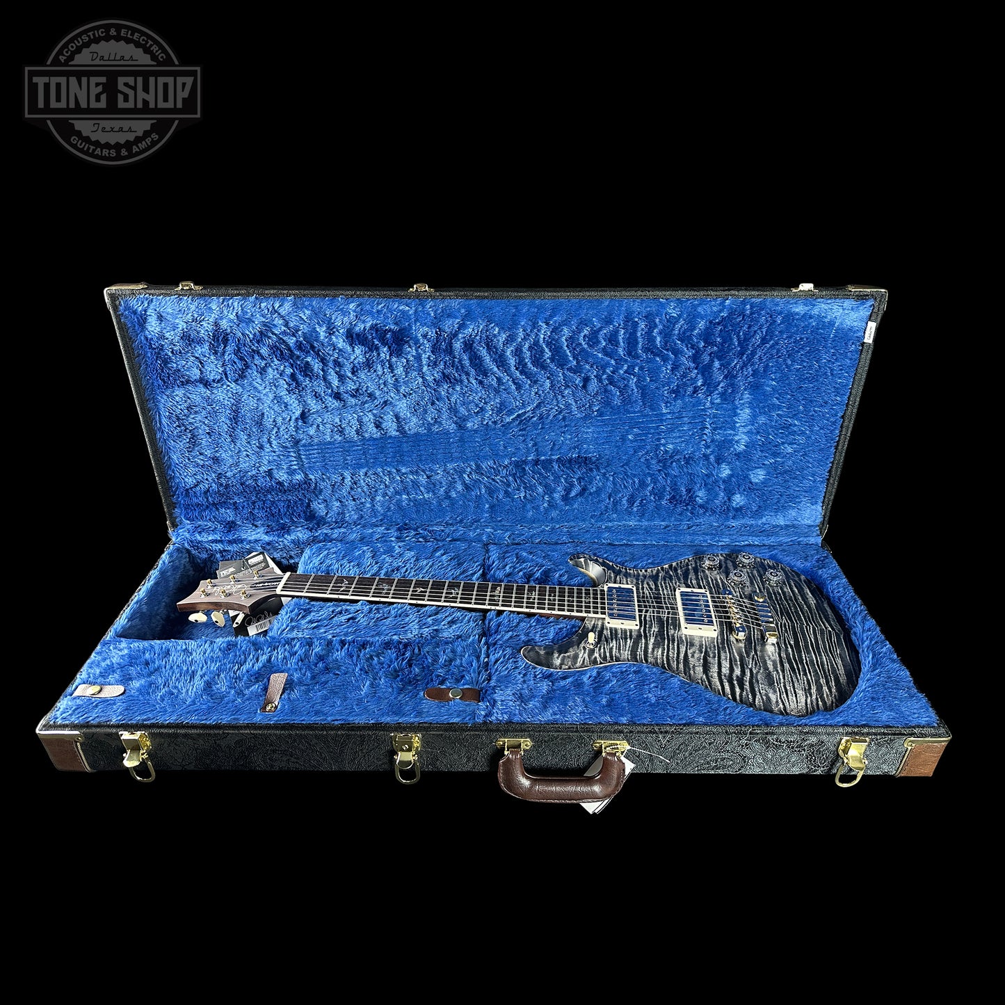 Electric guitar in an open blue case with 'Tone Shop' logo.