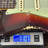 Guitar being weighed on a digital scale with a blue display.